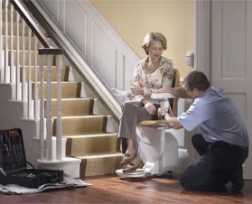 Man demonstrating stairlift use to a lady in a Bristol home