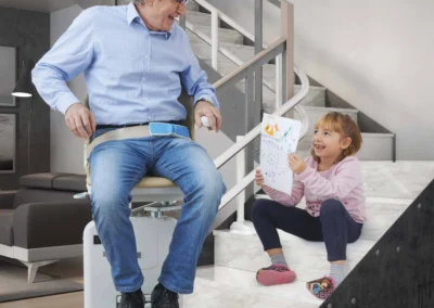 Senior and child smiling at bottom of curved stairlift in South Wales home
