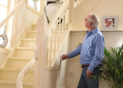 Man standing at the bottom of a curved stairlift installed in a South West home