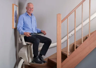 Hands On Stairlifts curved stairlift in use with man at bottom of stairs