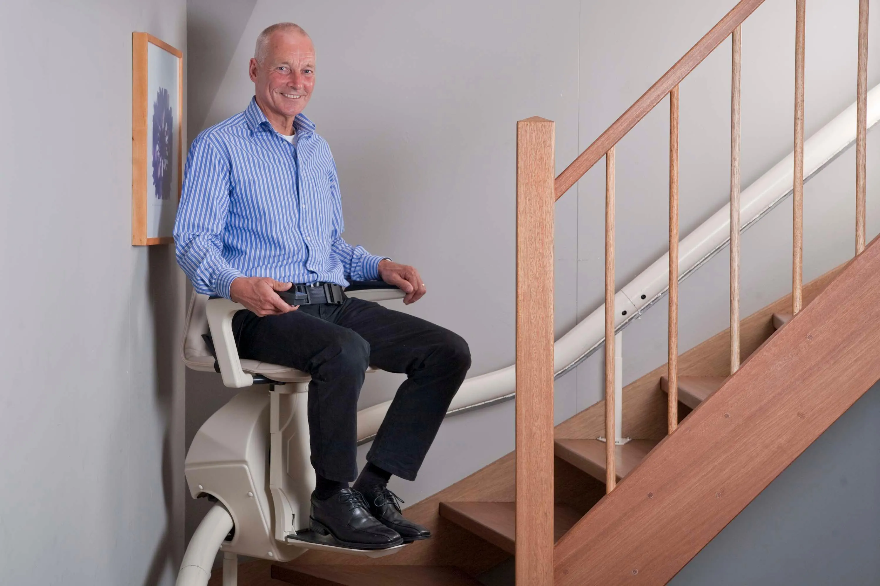 Hands On Stairlifts curved stairlift in use with man at bottom of stairs