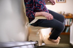 Detail Of Senior Woman Sitting On Stair Lift At Home To Help Mobility