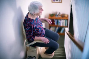 Elderly lady using curved stairlift in Bath home