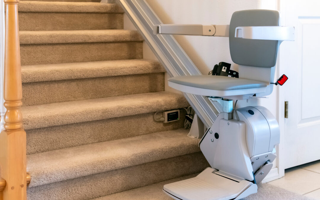 An electric stair lift for persons with disabilities on a carpeted staircase in a residential home.